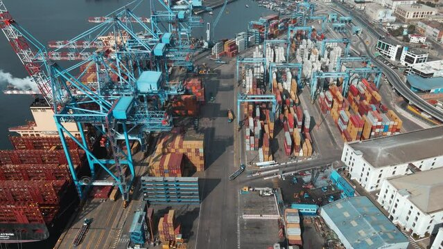 Aerial dolly in of a container cargo ship docked in Valparaiso Sea Port near cranes ready to be loaded, Chile