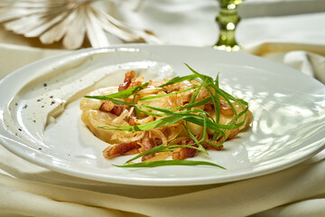 Varenyky with potatoes, fried onions and lard in a plate on a white tablecloth. Ukrainian cuisine
