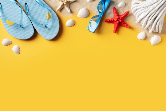 Summer holidays flat lay with shells, starfish and accessories on yellow background