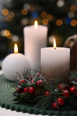 Obraz na płótnie Canvas Beautiful burning candles and Christmas decor on white table against festive lights