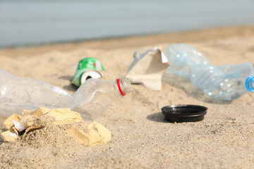 Fototapeta na wymiar Garbage scattered on beach near sea, closeup. Recycling problem