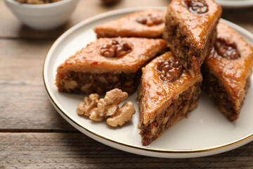 Fototapeta na wymiar Delicious honey baklava with walnuts on wooden table, closeup