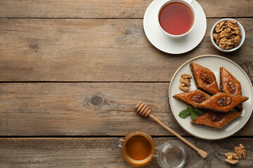 Delicious honey baklava with walnuts served on wooden table, flat lay. Space for text