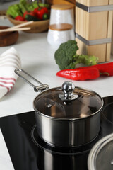 Metal saucepan on cooktop in kitchen. Cooking utensils