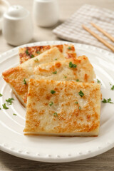Delicious turnip cake with parsley served on wooden table, closeup