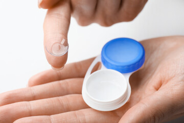 Woman holding case with contact lenses on white background, closeup