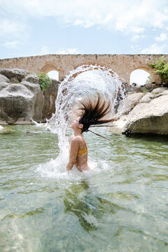 Spectacular picture of pretty girl splashing hair in a transparent water river.