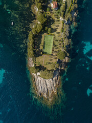 Top down drone shot of a tennis court surrounded by the sea in Provence, Saint Jean cap Ferrat town.