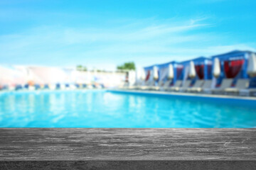 Empty stone surface near outdoors swimming pool with clear water. Space for design