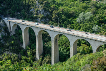 An historic arched bridge near Eze village close to Nice city with passing cars.