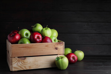 Fresh ripe red and green apples on black wooden table, space for text