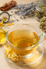 Freshly brewed tea and dried herbs on wooden table