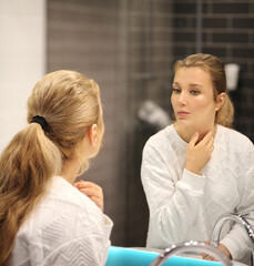 woman looking in the mirror in the bathroom and taking care of her skin.Applying the cream..Magic...