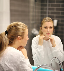 woman looking in the mirror in the bathroom and taking care of her skin.Applying the cream..Magic...