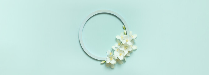 Beautiful flowers banner composition. White jasmine flowers, empty round frame for text on pastel...