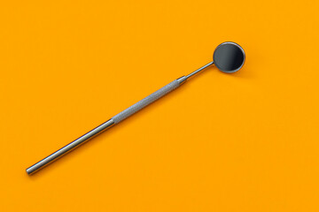 Dental mirror on an orange background. Medical tool