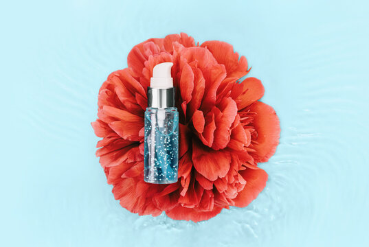 Hydration. Cosmetics medical skincare, mockup glass blue serum bottle with collagen on water waves and red peony flower. Advertising skin care product for anti-aging, moisturizing and cleansing.