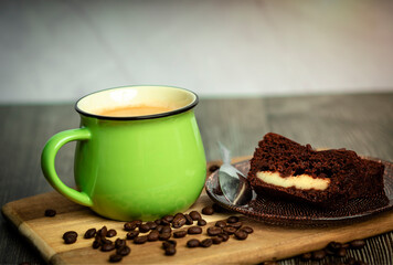 Chocolate cake and a green cup of coffee on a wooden table. Coffee.