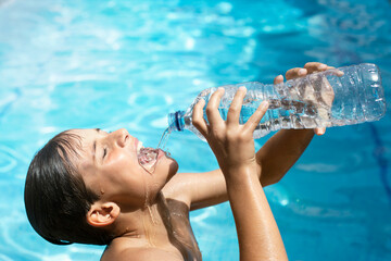 Heat wave.Happy young woman in the pool drinking water with a plastic bottle in her hands. Clean...