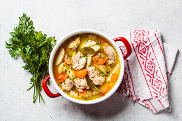 Chicken stew with potatoes and carrots in red saucepan. Chicken soup with vegetables and herbs....
