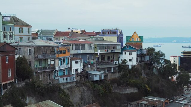Jib up of picturesque colorful hillside houses in Cerro Alegre, sea in background on an overcast day, Valparaiso, Chile