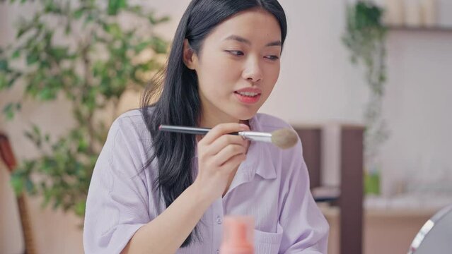 Asian woman recording makeup tutorial on cellphone, beauty blogging, giveaway