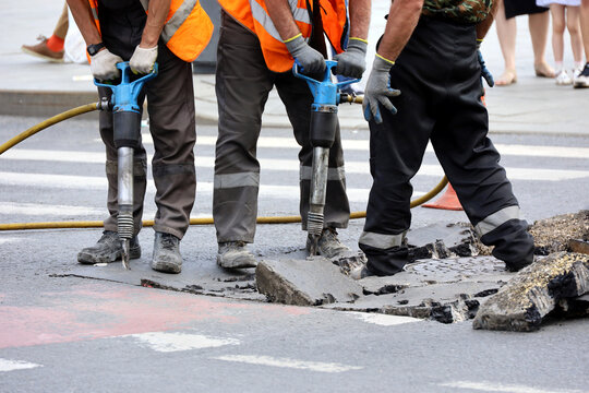 Workers repair the road surface with a jackhammers. Construction work, sewer repairing in city