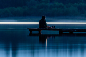 Fototapeta premium dziewczyna siedząca na molo nocą