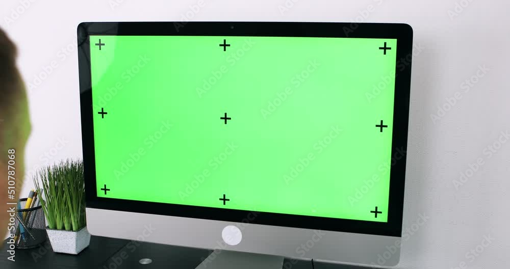 Poster green screen. employee working at computer sitting at desk. view from back.
