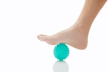 Close-up low section of man standing over massage ball against white background