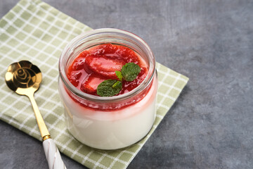 Sweet vanilla silky pudding dessert with strawberry sauce, sliced ​​fresh strawberries and mint on a glass
