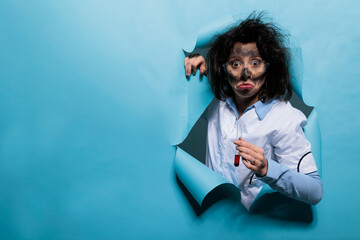 Crazy looking scientist with goofy face and messy hair holding glass test tube filled with...