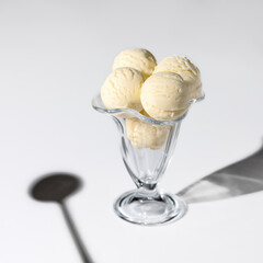 Portion of ice creame in the glass bowl and the shadow of spoon