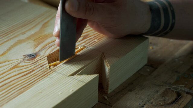 woodworker carving a dovetail eyelet with a chisel