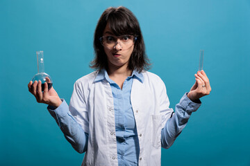 Laboratory professional chemist holding glass flasks filled with chemical liquid substances while...