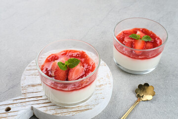 Sweet vanilla silky pudding dessert with strawberry sauce, sliced ​​fresh strawberries and mint on a glass
