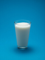 Glass of milk isolated on blue background.