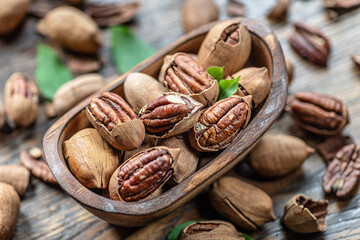 Shelled and cracked pecan nuts in the wooden bowl on wooden table. Top view.