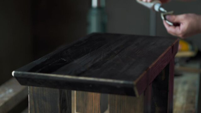 a woodworker using a swab to apply French polish to a black countertop and polish it with shellac
