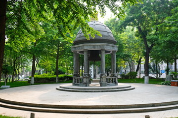 Beijing, China - 05.11.2019 : Stone gazebo with an old bell in the center of the city square.