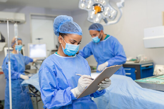 Surgeon writing on clipboard in operation room, anaesthesiologist writing the updates