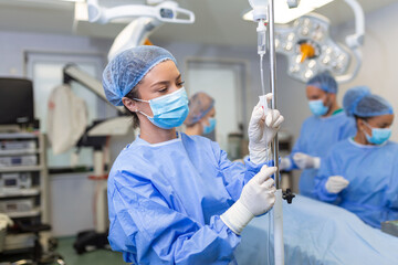 Female Doctor in the operating room putting drugs through an IV - surgery concepts