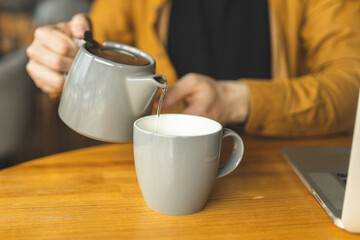 The man pours himself a cup of tea. Closeup of tea and mugs. Hot drink. Green tea.