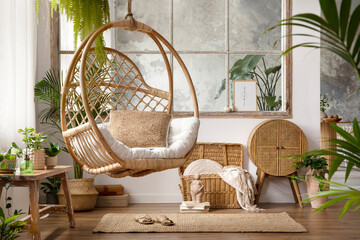 Fototapeta The stylish boho composition with changing swing, pouf , window, commode and wooden bench. Beige carpet with brown slippers. White wall. Template. obraz