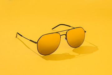 Aviator sunglasses on yellow background. Sunglass in sunlight for summer concept. Gold gradient on...