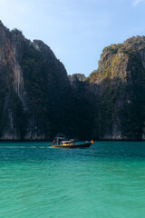 Long tail boat cruising through the turquoise waters of Koh phi phi led lagoon in Thailand