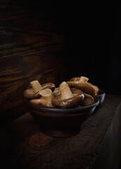Delicious pickled mushrooms in a beautiful clay cup .
