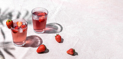 Summer refreshment concept with drinking glass filled with cold strawberry juice and ice
