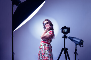 woman model illuminated by professional flashes in a photography studio while posing in a fashion shooting in horizontal shot