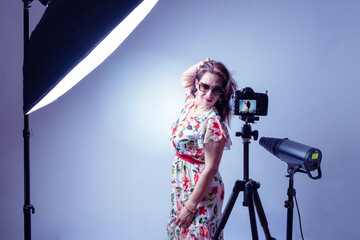 woman model illuminated by professional flashes in a photography studio touches her hair  while posing in a fashion shooting in horizontal shot